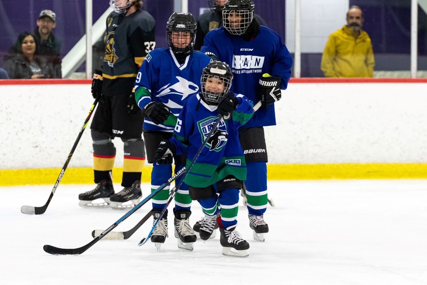Young Orcas players in blue jerseys skating up the ice together